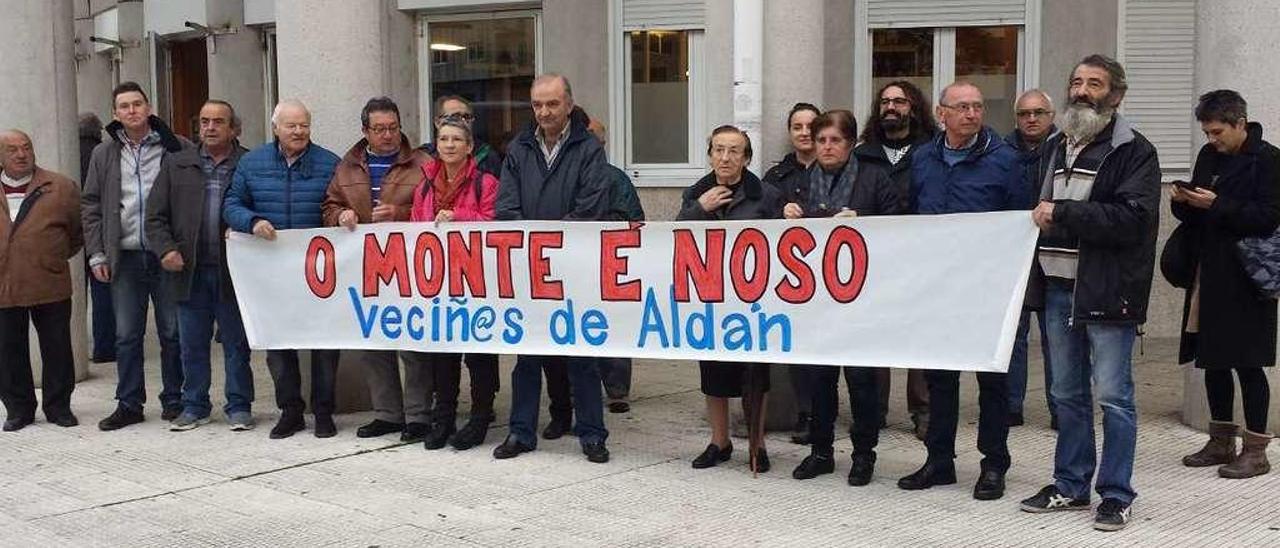 Vecinos portando una pancarta tras bajar del autobús que partió de Aldán. // Fran G. Sas