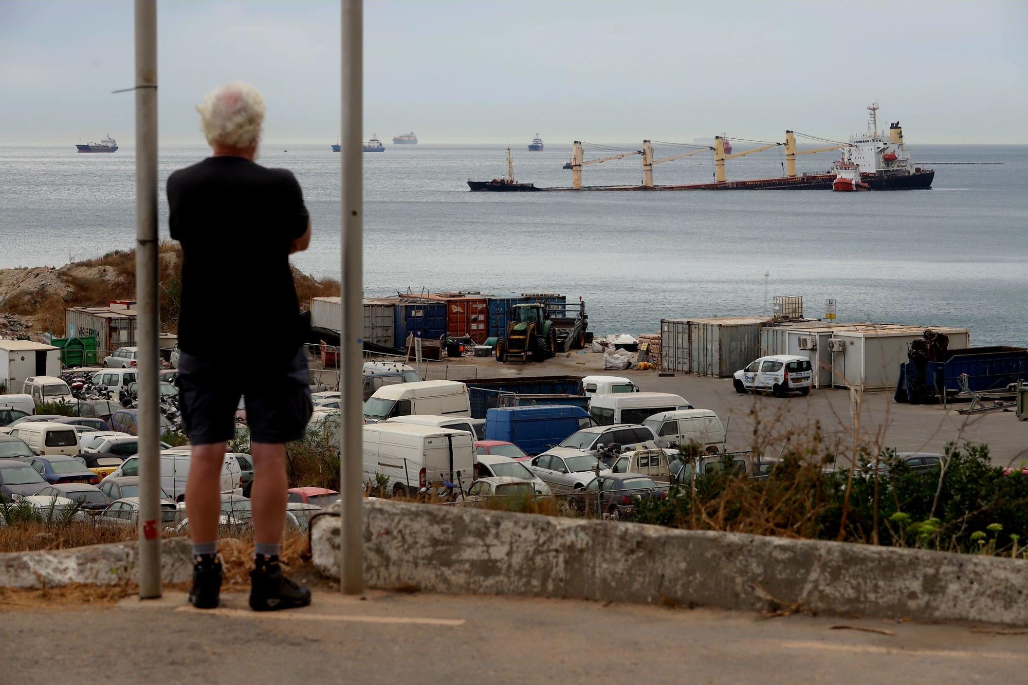 Personas en la playa observan como los equipos de salvamentos siguen evaluando y planificando el camino a seguir para extraer el combustible del buque granelero OS35 que permanece semihundido junto al Estrecho de Gibraltar.