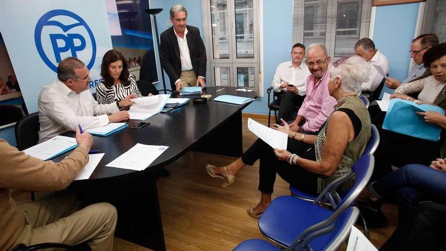 Carmen Rodríguez Maniega, en la mesa, junto a Carlos Rodríguez de la Torre, de pie, en una reciente reunión de la junta local del PP de Avilés.