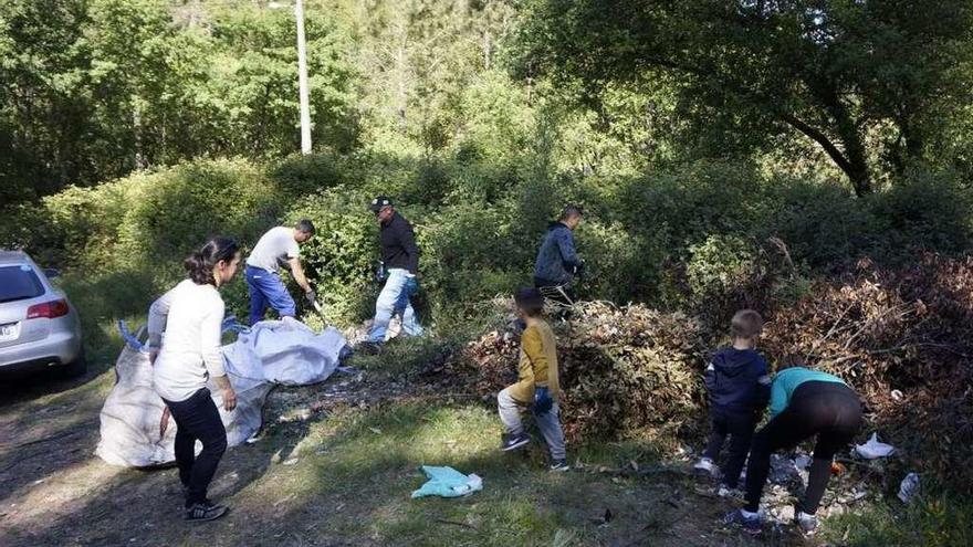 Socios de la asociación de vecinos de Chapela limpian los escombros en la parcela de A Lamosa. // FdV