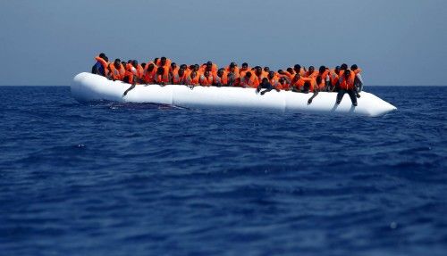 Migrants on a rubber dinghy wait to be rescued by the Migrant Offshore Aid Station ship MV Phoenix off the coast of Libya