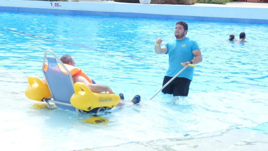 Unas persona discapacitada disfrutando de la piscina de olas junto a uno de los voluntarios