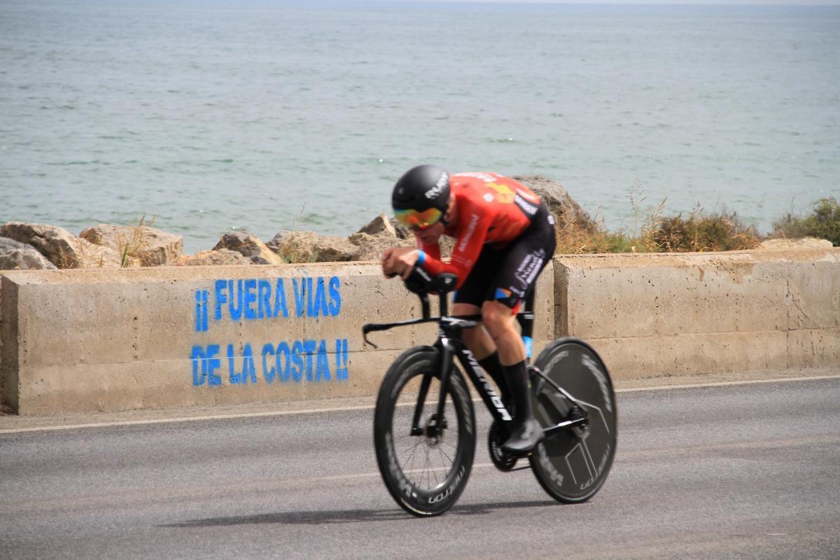 Un ciclista pasa por delante de un mensaje de protesta contra las vías en la costa