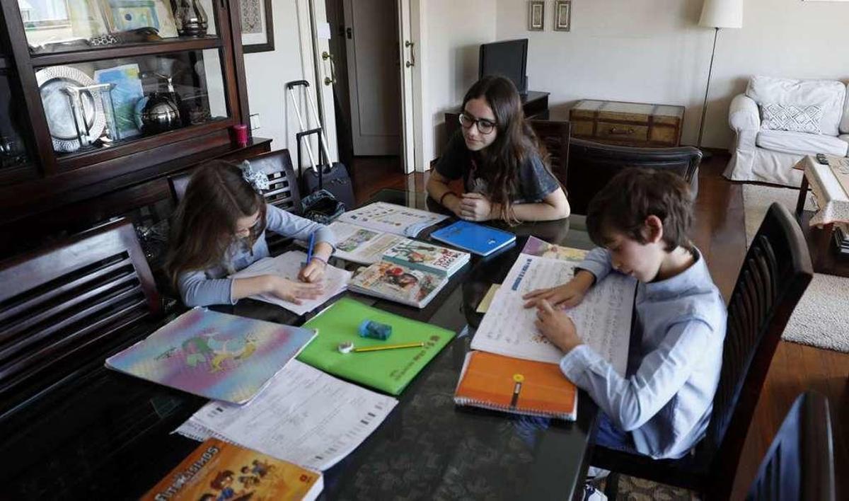 Carlota Sánchez (a la derecha) supervisa el trabajo de Alejandro y Alcázar, ayer, en el domicilio de los pequeños.