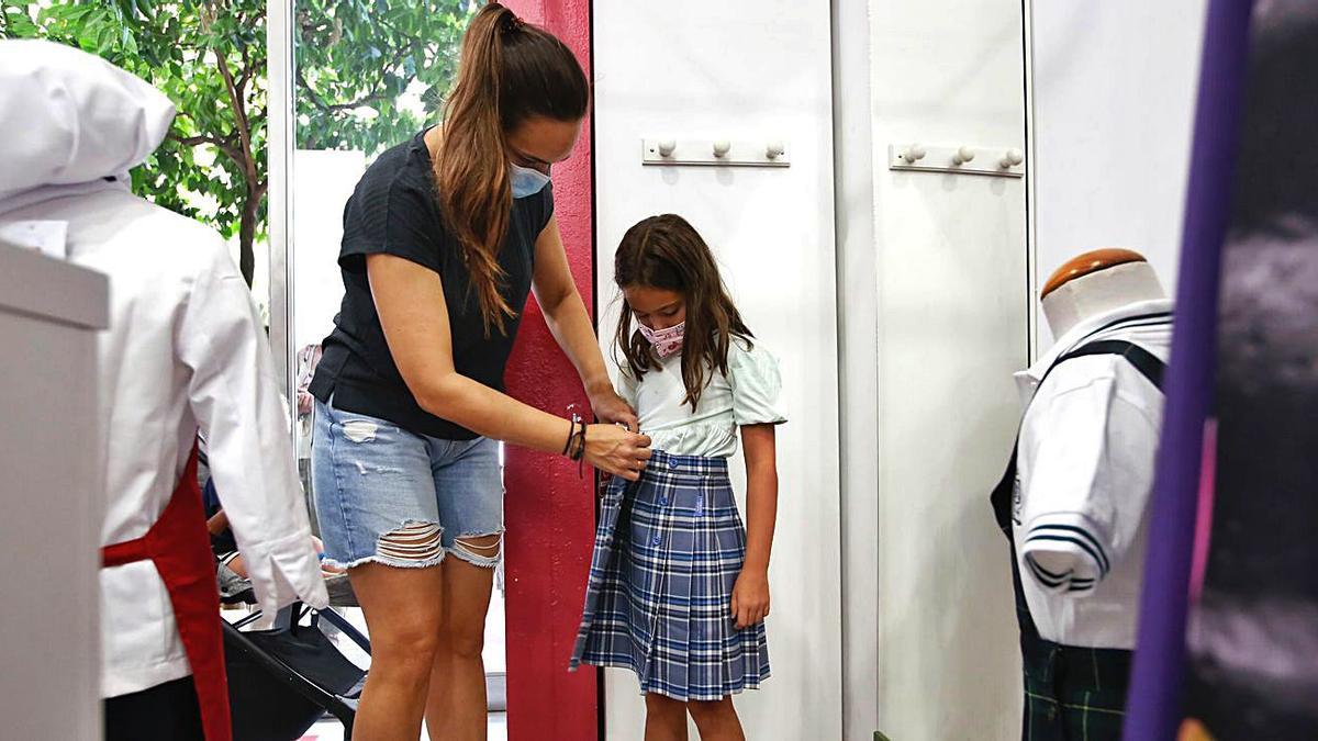 Una madre le prueba una falda de uniforme a su hija.