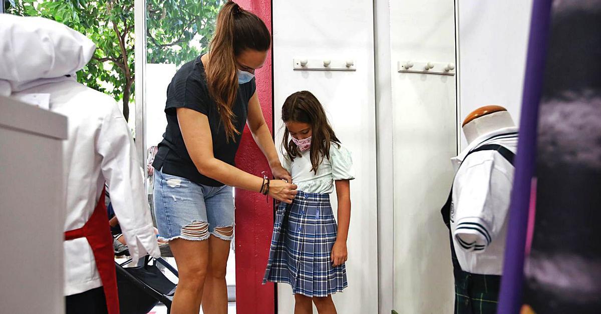 Una madre le prueba una falda de uniforme a su hija.