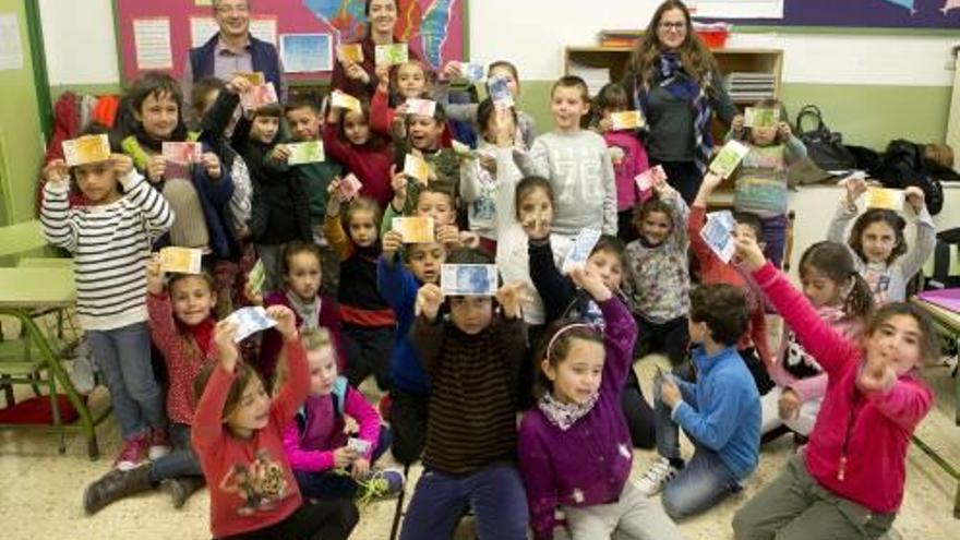 Niños y niñas de primero de primaria del CEIP Mora Puchol posan con sus profesoras y Francisco José, voluntario del BBVA, que les ha enseñado los valores del dinero.