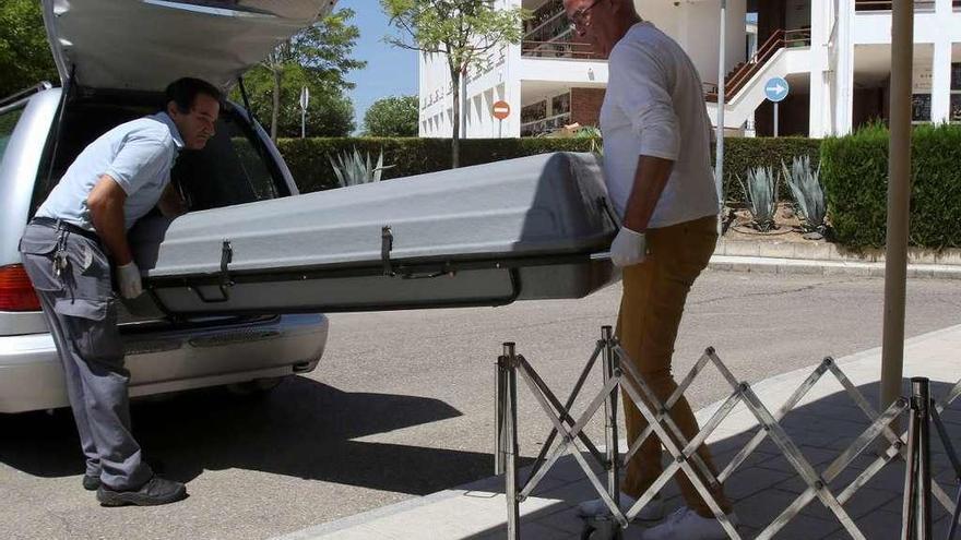 Dos operarios de una funeraria trasladan el féretro con el cuerpo de Miguel Blesa.