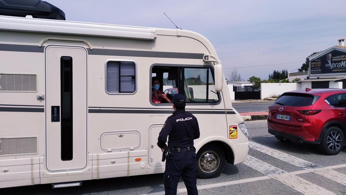 Un policía habla con los ocupantes de una caravana en la entrada a Dénia