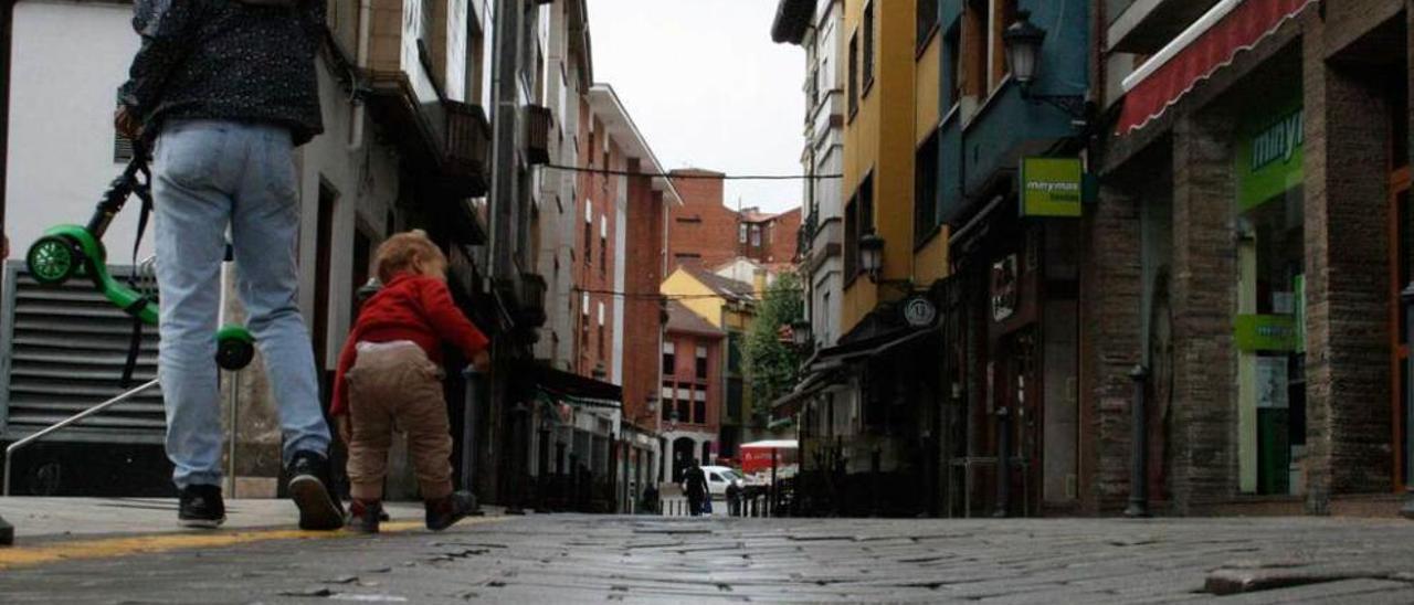 Una mujer y su hijo, en un tramo con baches de la calle Valdés Pumarino, ayer.