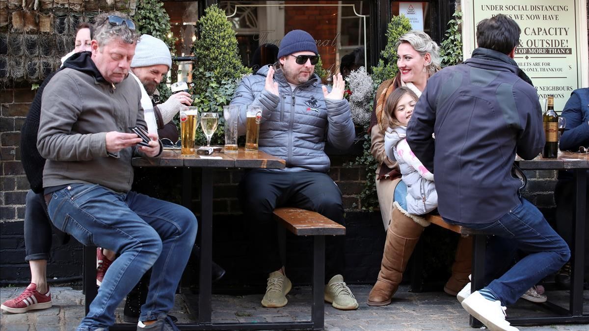 People drink at the terrace of a pub  next to a picture of Prince Philip  husband of Queen Elizabeth  as the coronavirus disease (COVID-19) restrictions ease  in London  Britain  April 12  2021  REUTERS Peter Cziborra