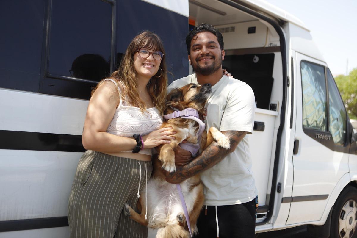 La pareja madrileña junto a su perra al lado de su caravana