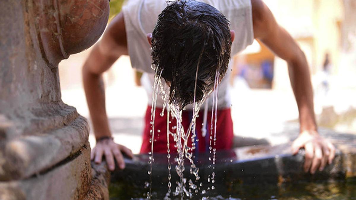 Un muchacho se refresca en una fuente de Córdoba.