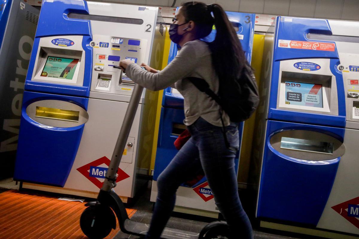 Una mujer entra con un patinete eléctrico en el metro.