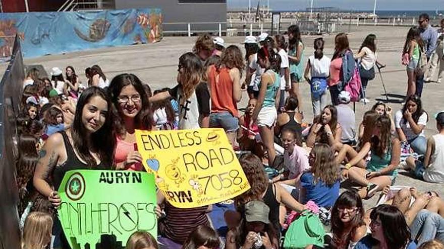 A la izquierda, adolescentes esperando a pie del escenario de Poniente. A la derecha, fans de «Auryn» enseñan pancartas con mensajes. | marcos león