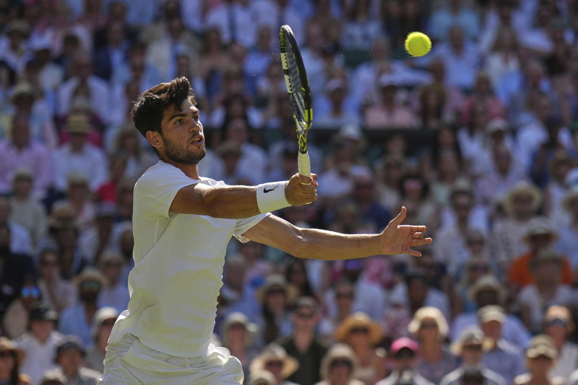 Spain's Carlos Alcaraz returns to Taylor Fritz of the U.S. in a men's singles semifinal at the Wimbledon Tennis Championships in London, Friday, July 11, 2025. (AP Photo/Kin Cheung)