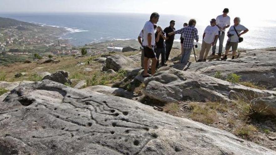 Los promotores de la &quot;Ruta Máxica&quot; en el alto de A Pedreira, uno de los puntos del camino que ofrece petroglifos y espectaculares vistas.  // J. Santomé