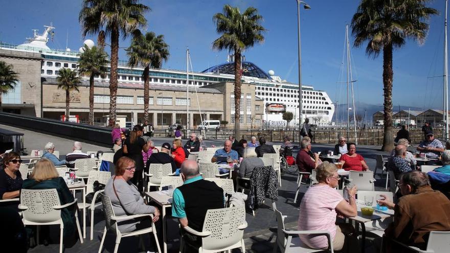 Pasajeros del &quot;Oceana&quot; (al fondo), en una terraza durante su escala en Vigo.