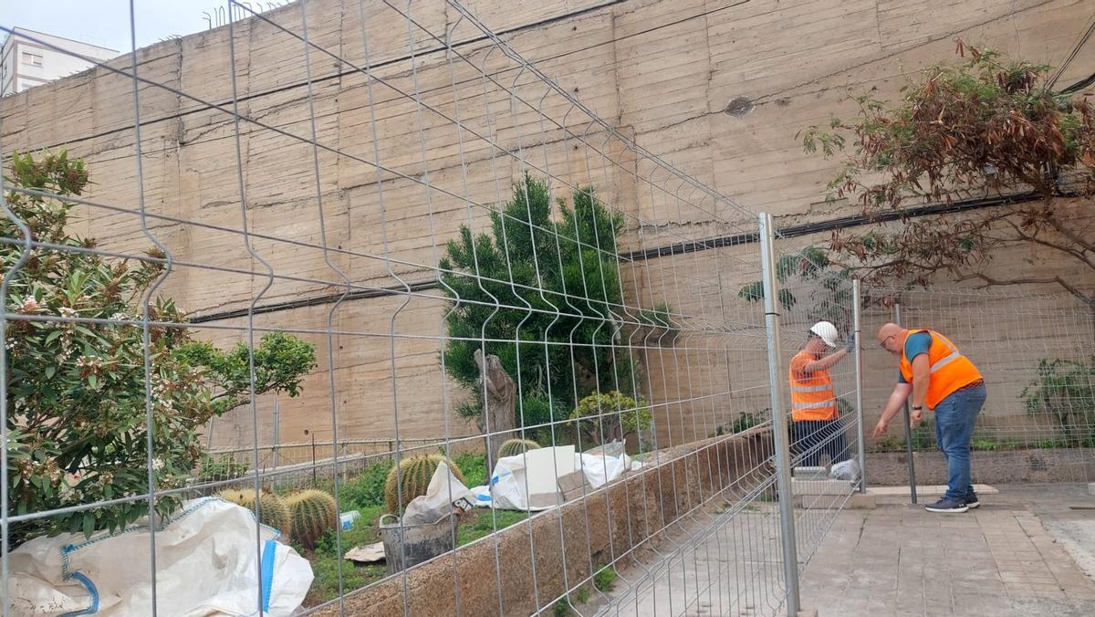 Dos técnicos colocan las vallas de seguridad para realizar las obras en el muro de Miller Bajo