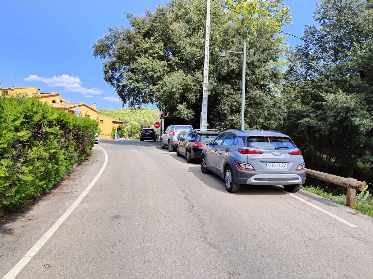 Cotxes aparcats, ocupant un tram de la carretera, a l'entrada del bar de l'alcalde