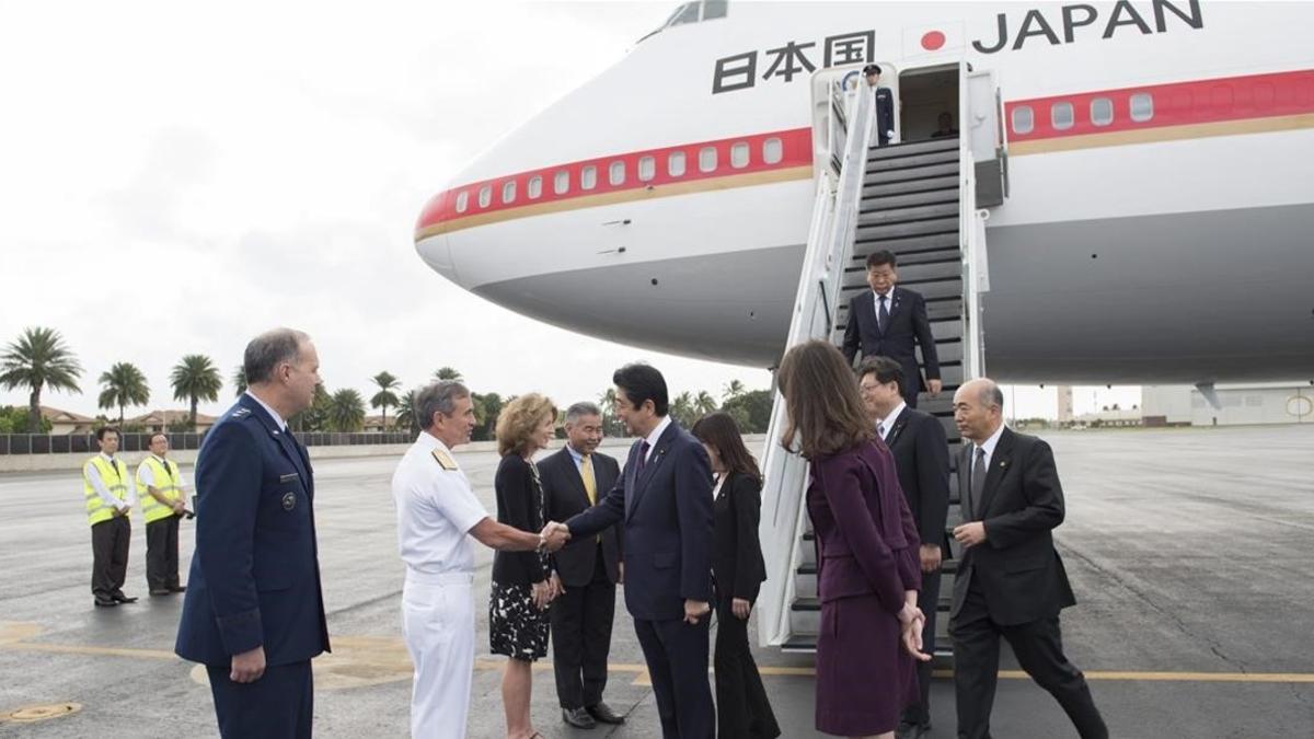 El primer ministro japones, Shinzo Abe, en el centro, es recibido por un comandante estadounidensse a su llegada a Pearl Harbor.