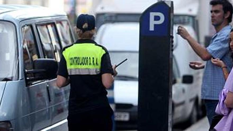 Una controladora de Park Control revisa los tickets de los vehículos estacionados en zona azul.