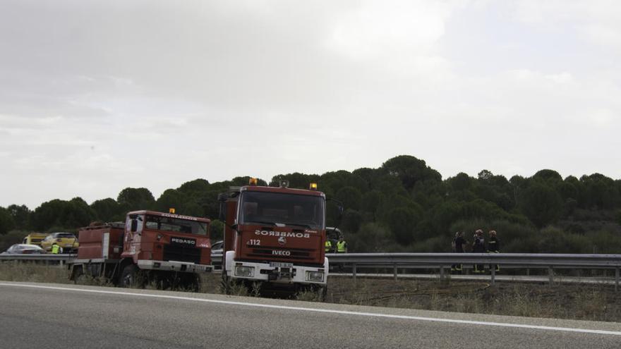 Escenario del accidente. A la izquierda el vehículo incendiado ya cargado en un camión detrás de dos agentes.