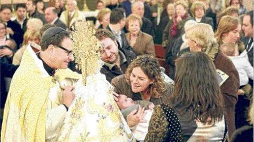 Un recién nacido mientras es bendecido por el prior, delante de la imagen de la Virgen.