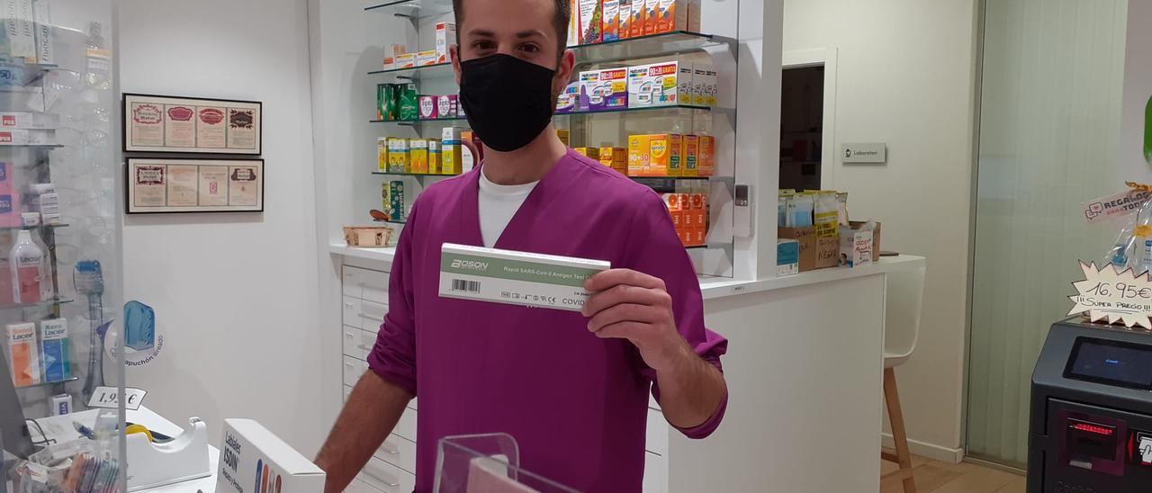 Un empleado de la farmacia Piña Fuster muestra un autotest reservado para un cliente