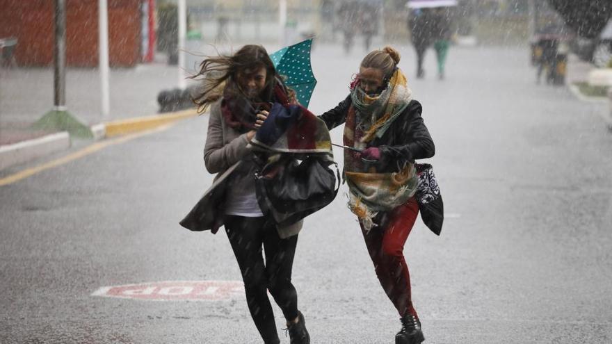 Dos chicas bajo la lluvia en el recinto ferial Luis Adaro.