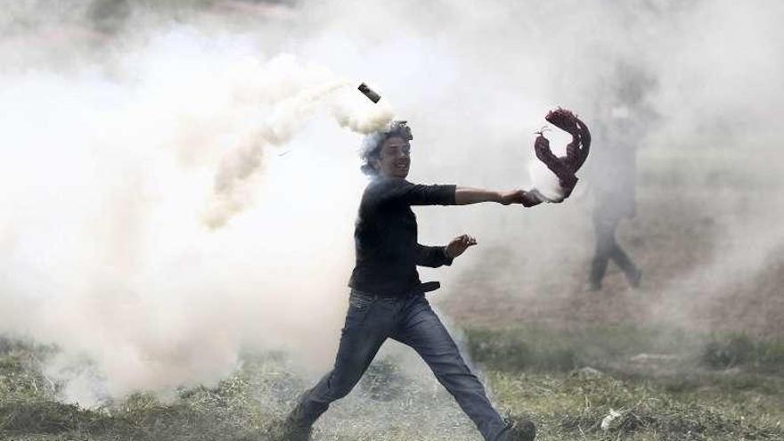 Un refugiado devuelve un bote de gas lacrimógeno en Idomeni. // Efe