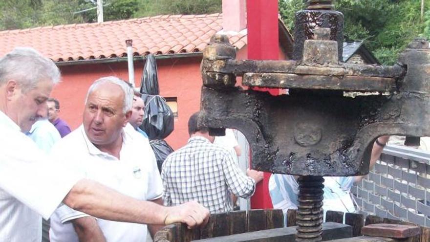 Visitantes del Museo del Vino de Cangas frente a una prensa antigua.