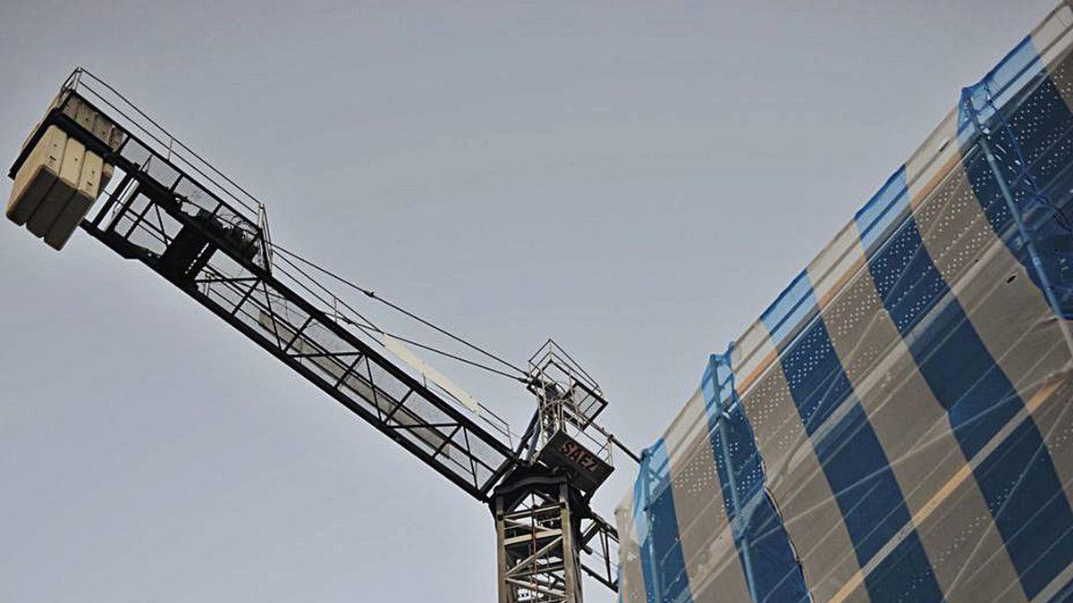 Una grúa junto a un edificio en construcción.