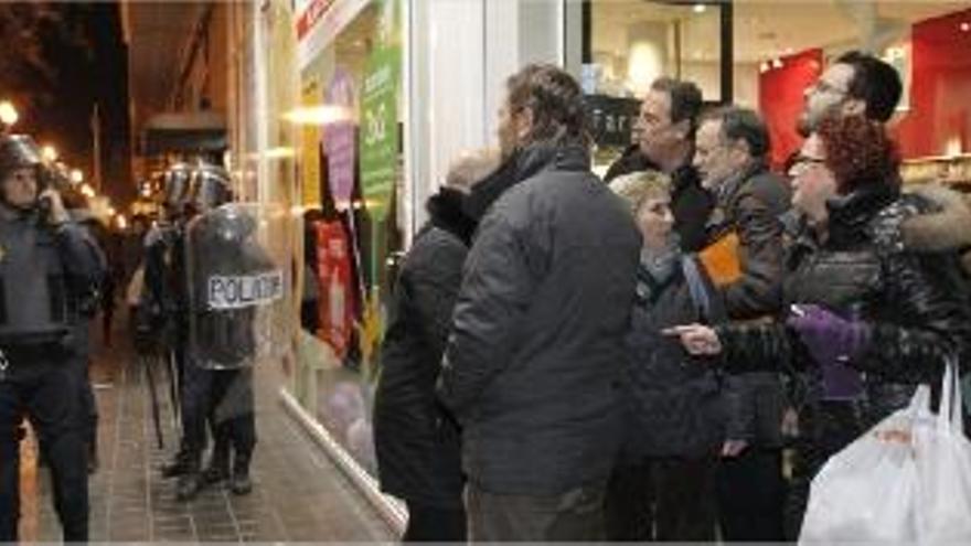 Varias personas, a la puerta de una farmacia, increpando a la Policía este lunes en Valencia.