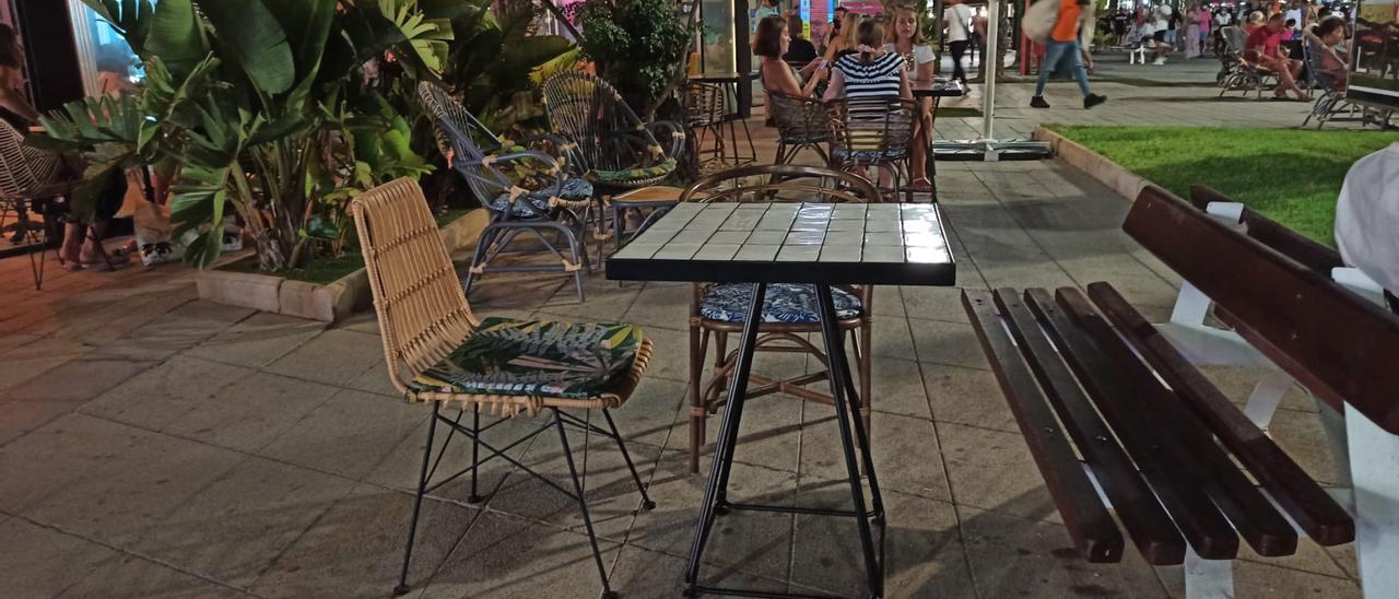 Mesa  y sillas de una terraza del paseo Juan Aparicio de Torrevieja con &quot;refuerzo&quot; de un banco público integrado