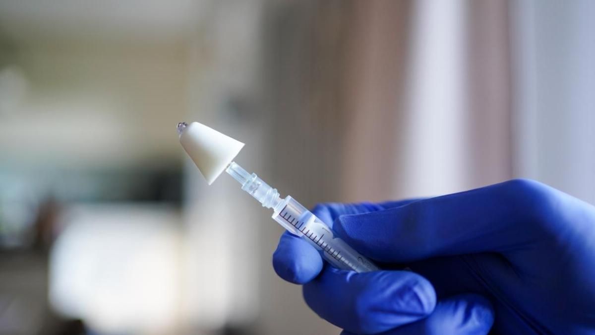 Una sanitaria se dispone a administrar la vacuna de la gripe.