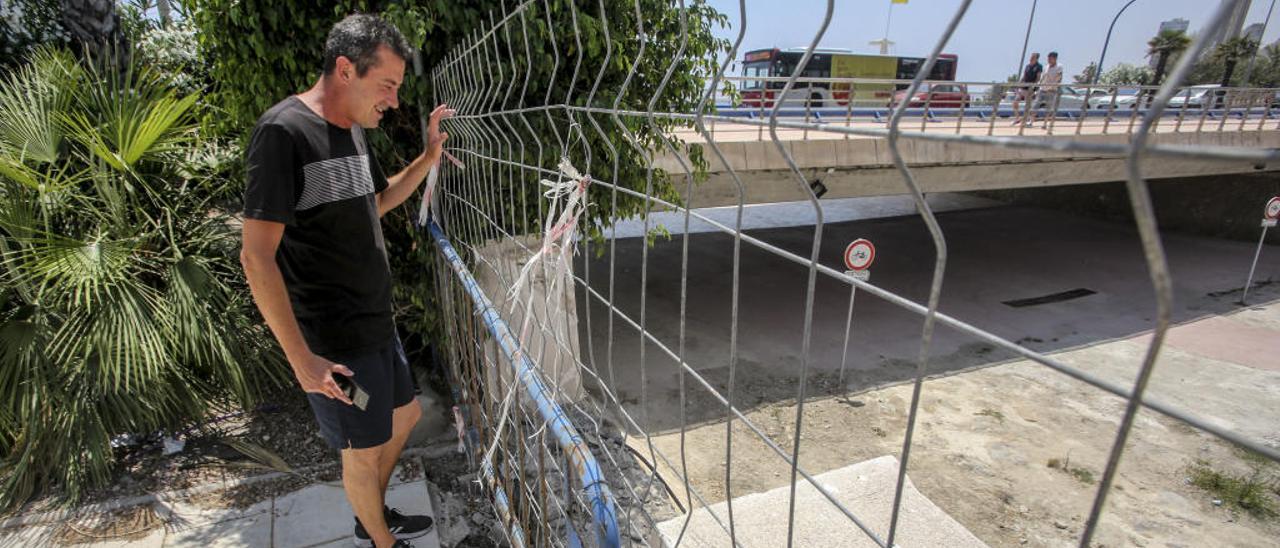 Un hombre observa la zona vallada por donde se accedía al barranco que comunica con la playa.