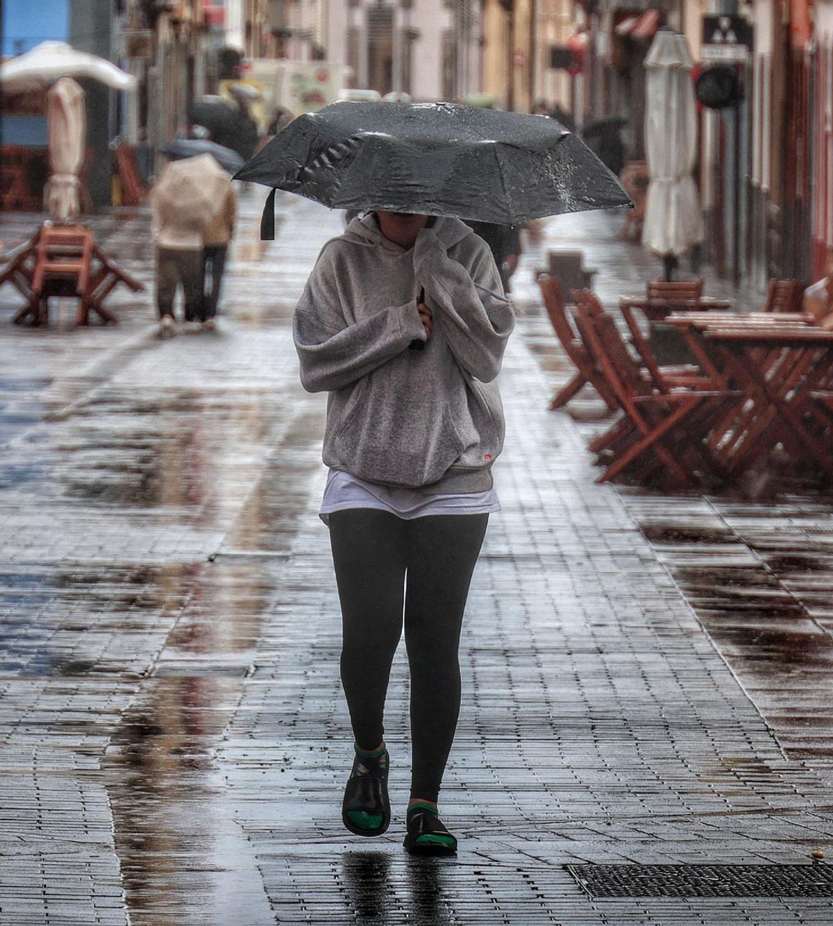 Una joven se protege de la lluvia ayer en el casco histórico de La Laguna. | MARÍA PISACA