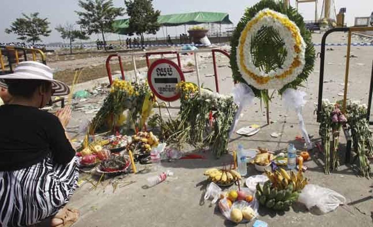 Dues persones resen per les 378 víctimes que dilluns passat van morir al quedar atrapades en un pont de vianants que connecta la capital cambodjana, Phnom Penh, amb l’illa de Koh Pich, durant el Festival de l’Aigua.