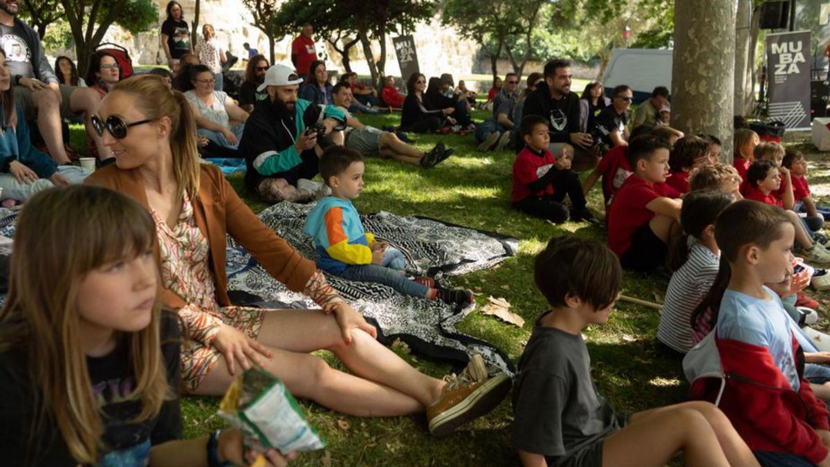 Jóvenes y adultos disfrutan del festival sentados en el césped. | J.L.F.