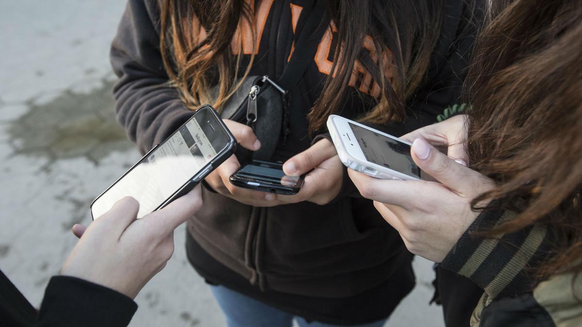 Un grupo de menores consulta su teléfono móvil.