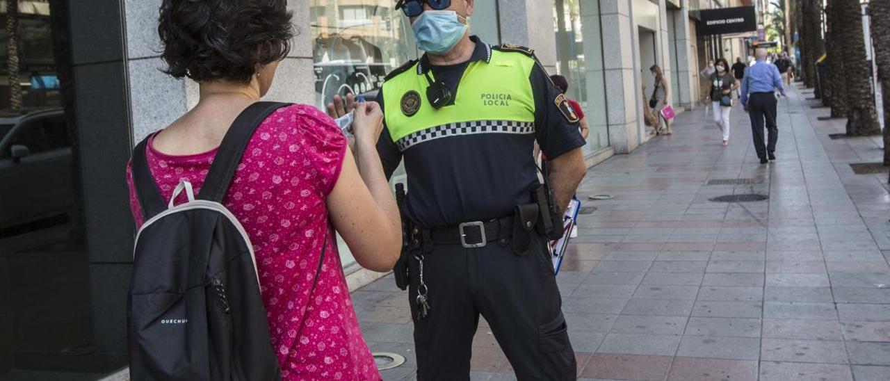 Un policía local controlando el uso de mascarillas en el centro de Alicante.