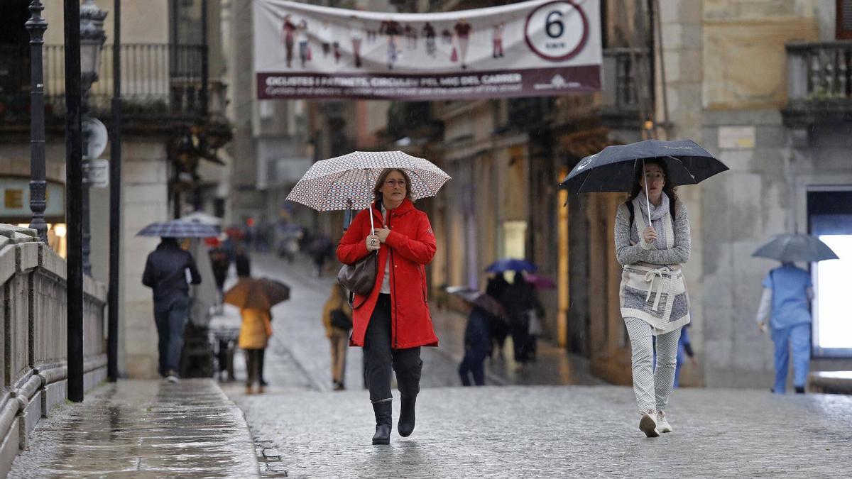 Dues dones caminen per Girona sota la pluja