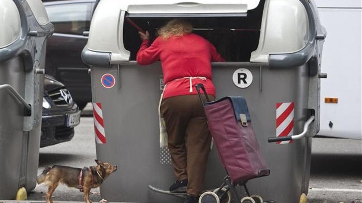 Una mujerbusca en el interior de un contenedor, en Barcelona.