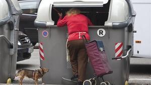 Una mujer rebusca en el interior de un contenedor, en Barcelona.