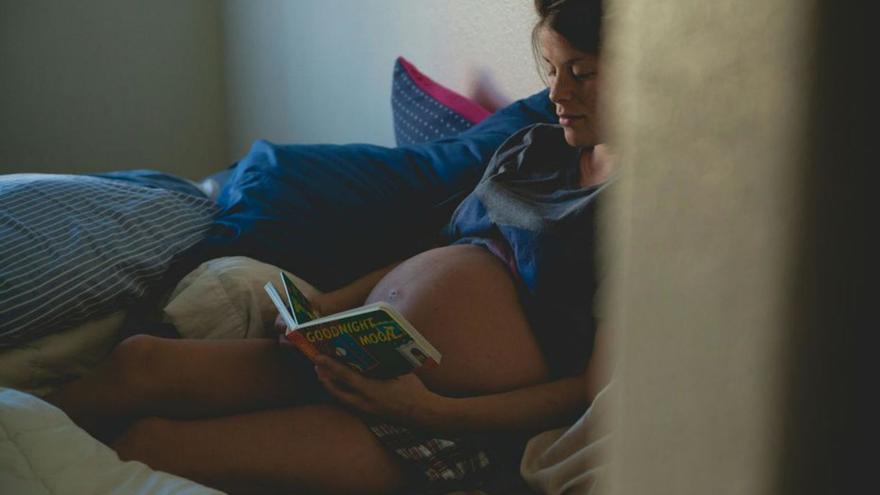 Una joven embarazada, leyendo en la cama. |Josh Willinkt/ Pexels
