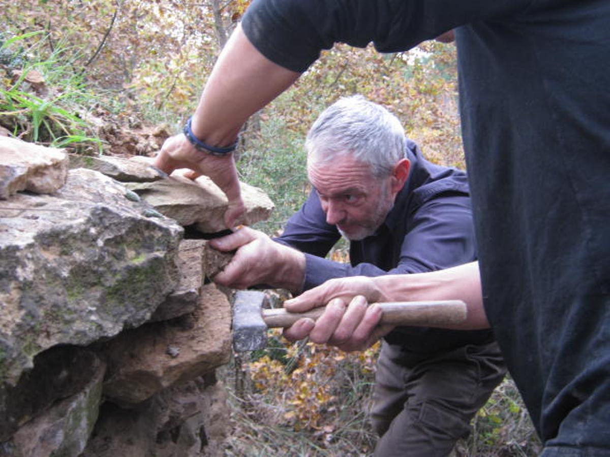 Dos participants en un taller de construcció de mur de pedra seca