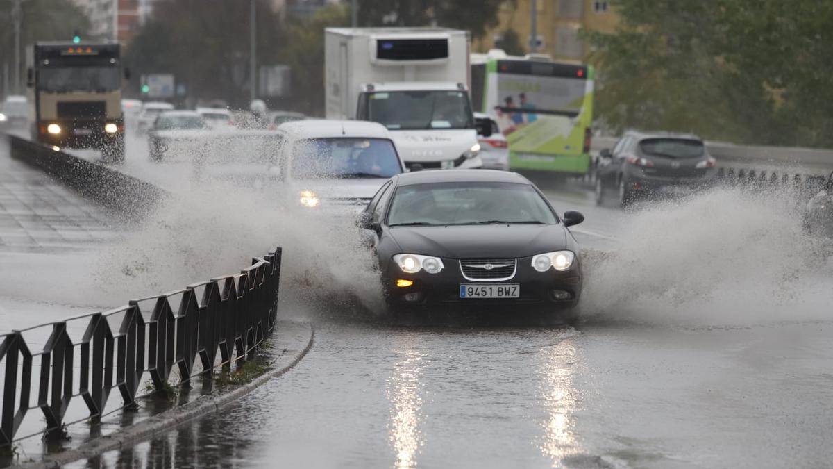 Un coche levanta agua acumulada en el Puente de San Rafael tras las persistentes lluvias.