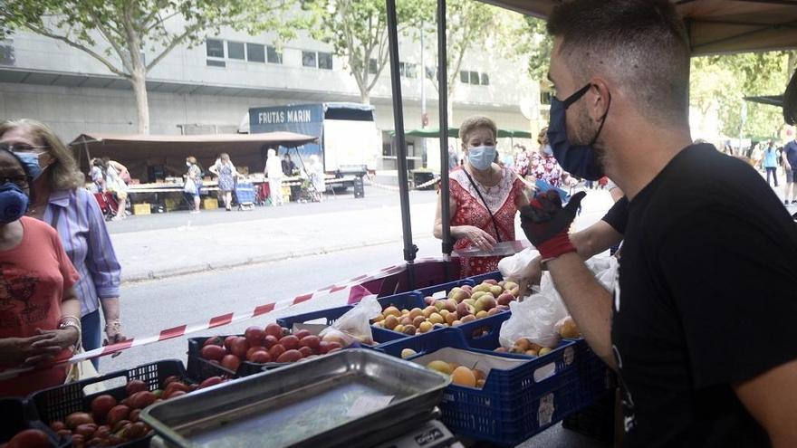 Un tendero atiende a varios clientes en su puesto en el mercado semanal de La Fama.