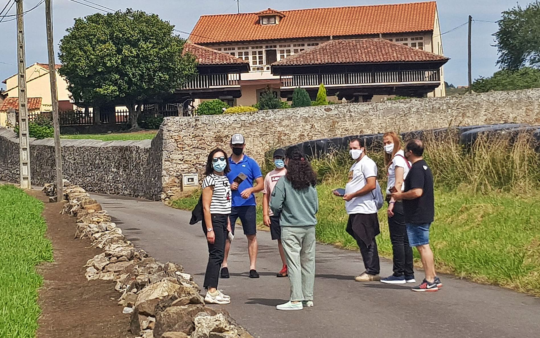 Belén Rodríguez y Christopher Mitchell –los dos con camisetas blancas– ejercen de guías de un grupo con el que se disponen a visitar las paneras de Casa la Viuda, al fondo.